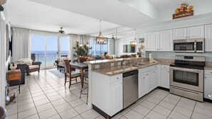 A modern kitchen with a central island, stainless steel appliances, and a view to the ocean. - Beachfront Bliss, Majestic Sun A1002 | Stunning Gulf Views & Resort Amenities (Miramar Beach)