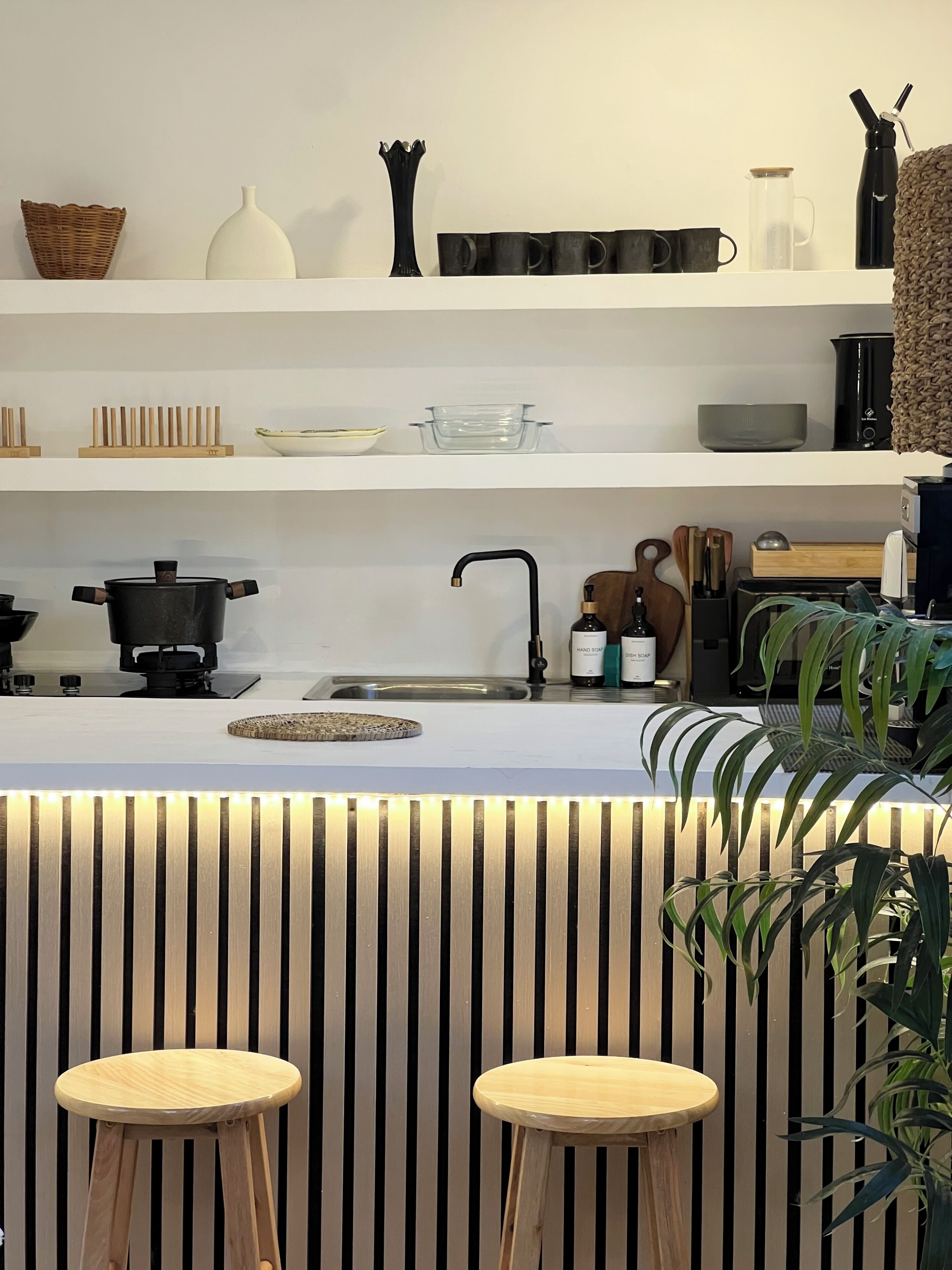 A modern kitchen with white cabinetry, a built-in stove, and a bar area with stools.
