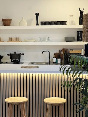 Une cuisine moderne dotée d’un îlot central, d’un évier et de divers ustensiles de cuisine et accessoires.