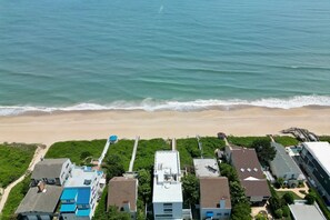 Vista aérea de una zona costera con playa, casas y una carretera que conduce a la playa.
