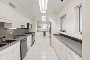 Una cocina moderna con armarios blancos, una estufa de acero inoxidable y un ventanal grande.