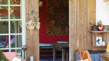 A wooden interior with a red wall, a tapestry, and a small table with a chair.