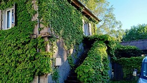 A building partially covered with green ivy, a visible window, and a staircase leading to an upper level. - Holiday Home “La Voyageuse” with Private Terrace, Garden & Wi-Fi (Gorses)