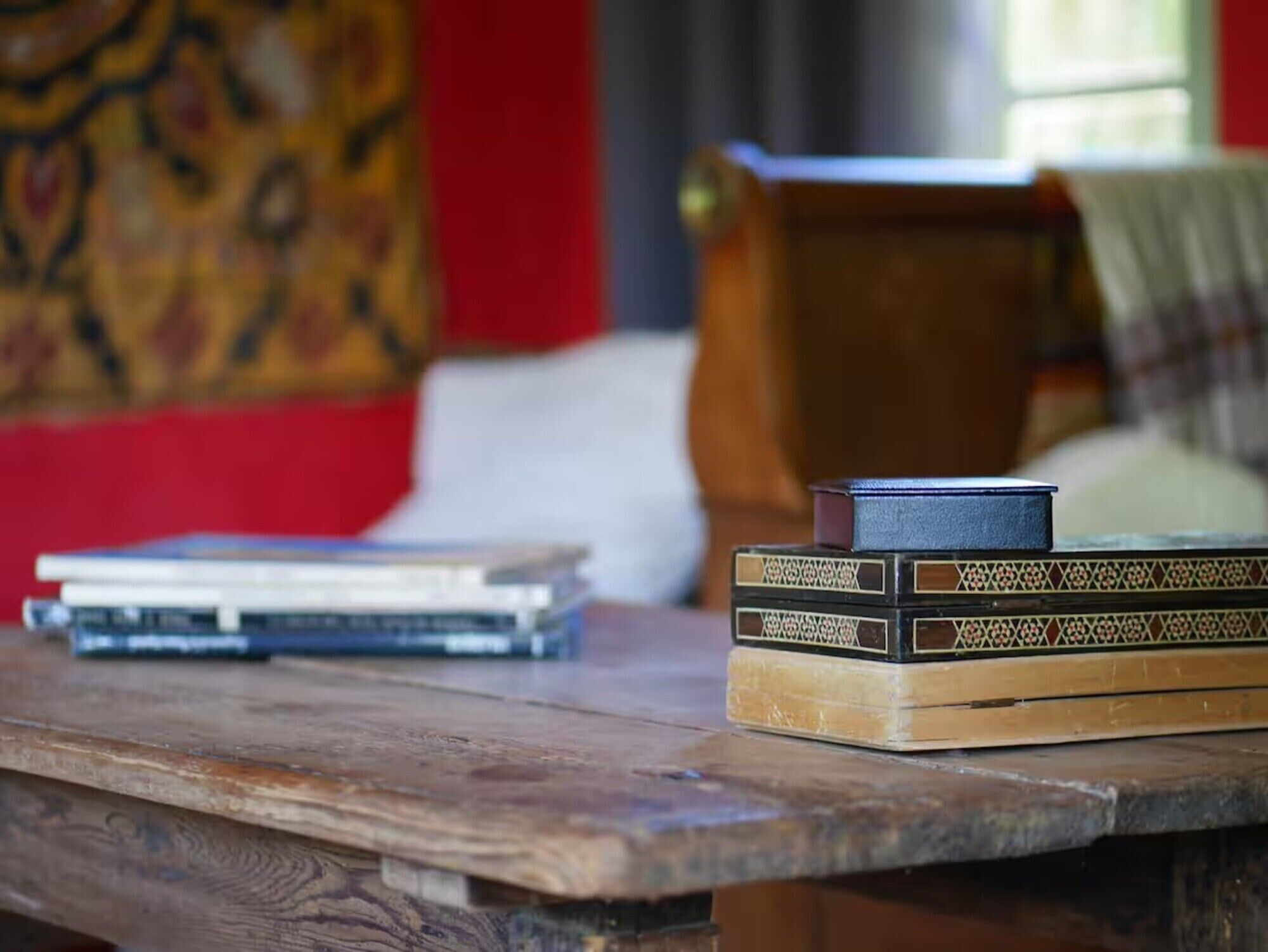 Una mesa de madera con libros y un objeto negro pequeño encima.