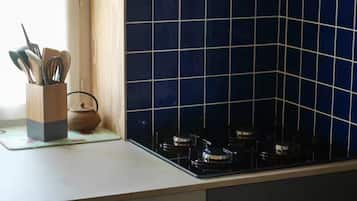A kitchen with a gas stove, a wooden utensil holder, and a blue-tiled backsplash.