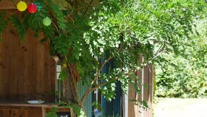 A wooden structure with a bench, a sign with a frog symbol, and a blue door. - Holiday Home “La Voyageuse” with Private Terrace, Garden & Wi-Fi (Gorses)