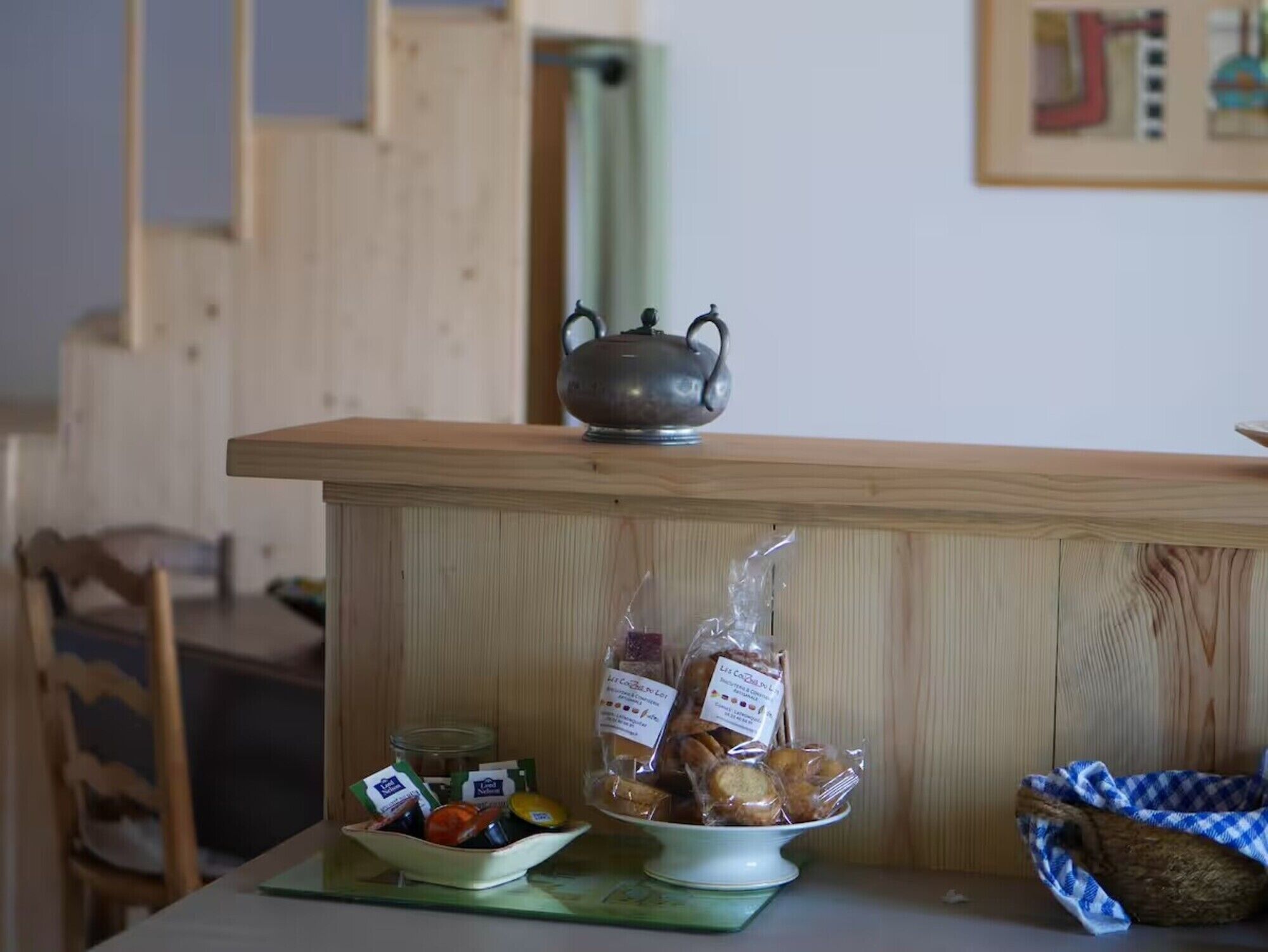 Una encimera de madera con una tetera, frascos y alimentos envasados.