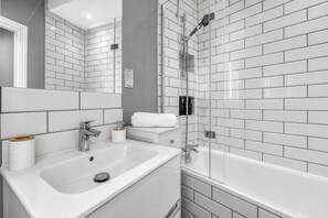A modern bathroom with a white sink, mirror, and shower. - Stylish 2BR Home With Full AC 1 Bathroom Sleeps 4 (London)