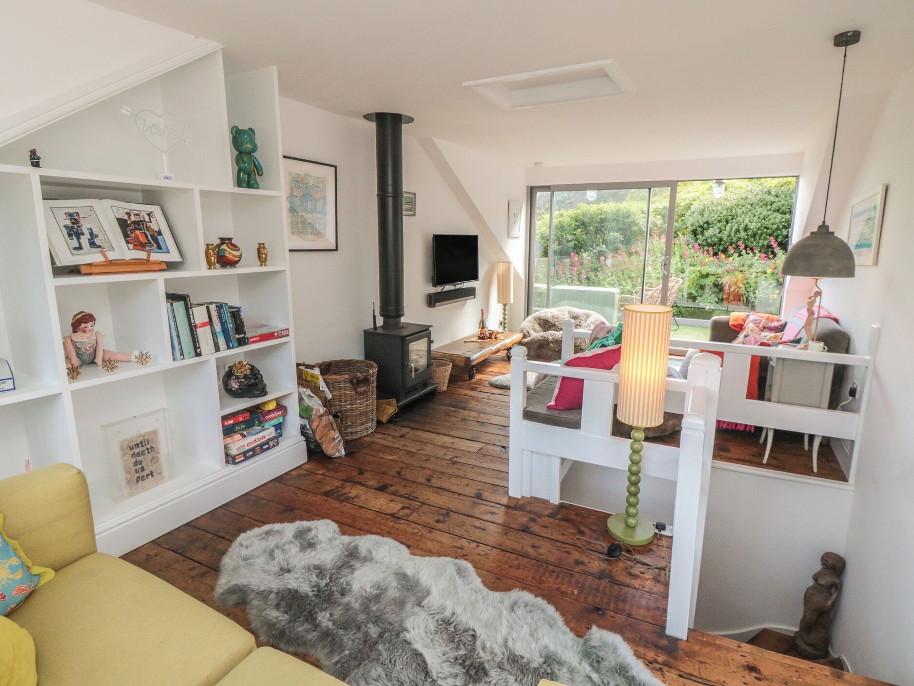 A cozy living room with a fireplace, a sofa, a white chair, and a bookshelf.
