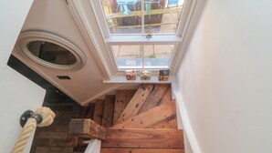 Una escalera de madera con tragaluz y barandilla de cuerda.