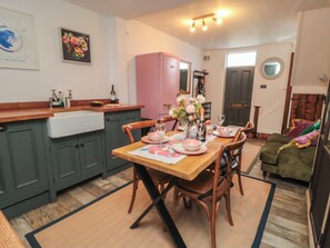 A kitchen with a dining table set for four, a pink refrigerator, and a green cabinet.