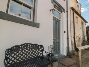 A white building with a green door, a bench, and a small garden area. - Hillsover (Saltburn-by-the-Sea)
