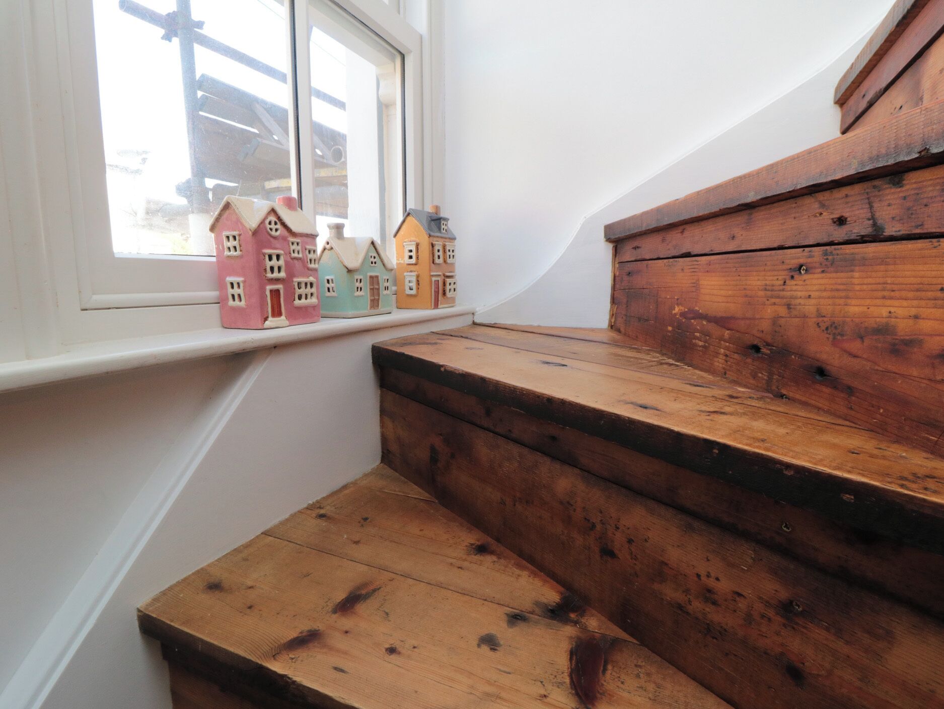 Unos escalones de madera conducen a un alféizar con casas en miniatura de colores.