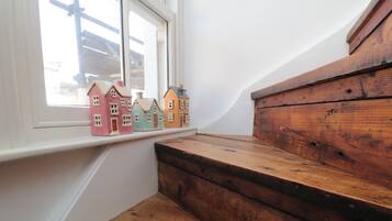 Unos escalones de madera conducen a un alféizar con casas en miniatura de colores.