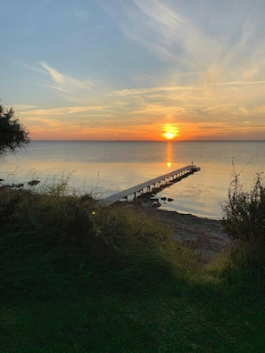 Un capvespre sobre un mar tranquil amb un moll de fusta que s'endinsa a l'aigua.