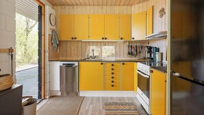 Une cuisine avec des armoires jaunes, des appareils en acier inoxydable et un plafond en bois.