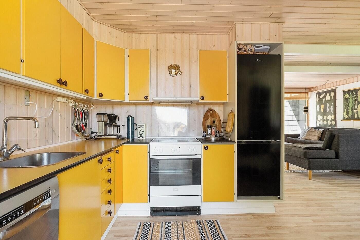A compact kitchen with yellow cabinets, a stove, and a refrigerator.