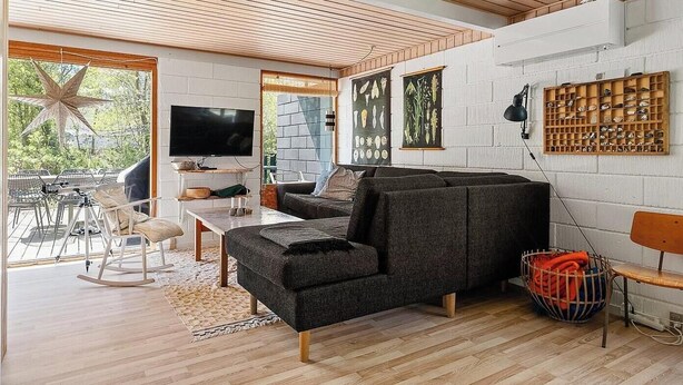 Un salon moderne avec un canapé, un téléviseur et un plafond en bois.