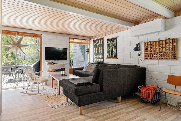 Ein modernes Wohnzimmer mit Sofa, Fernseher und Holzboden.