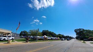 A street with a clear sky, a flagpole with an American flag, and a row of tents on the side. - Brand new construction quiet neighborhood fire pit screened porch (Sawyer)