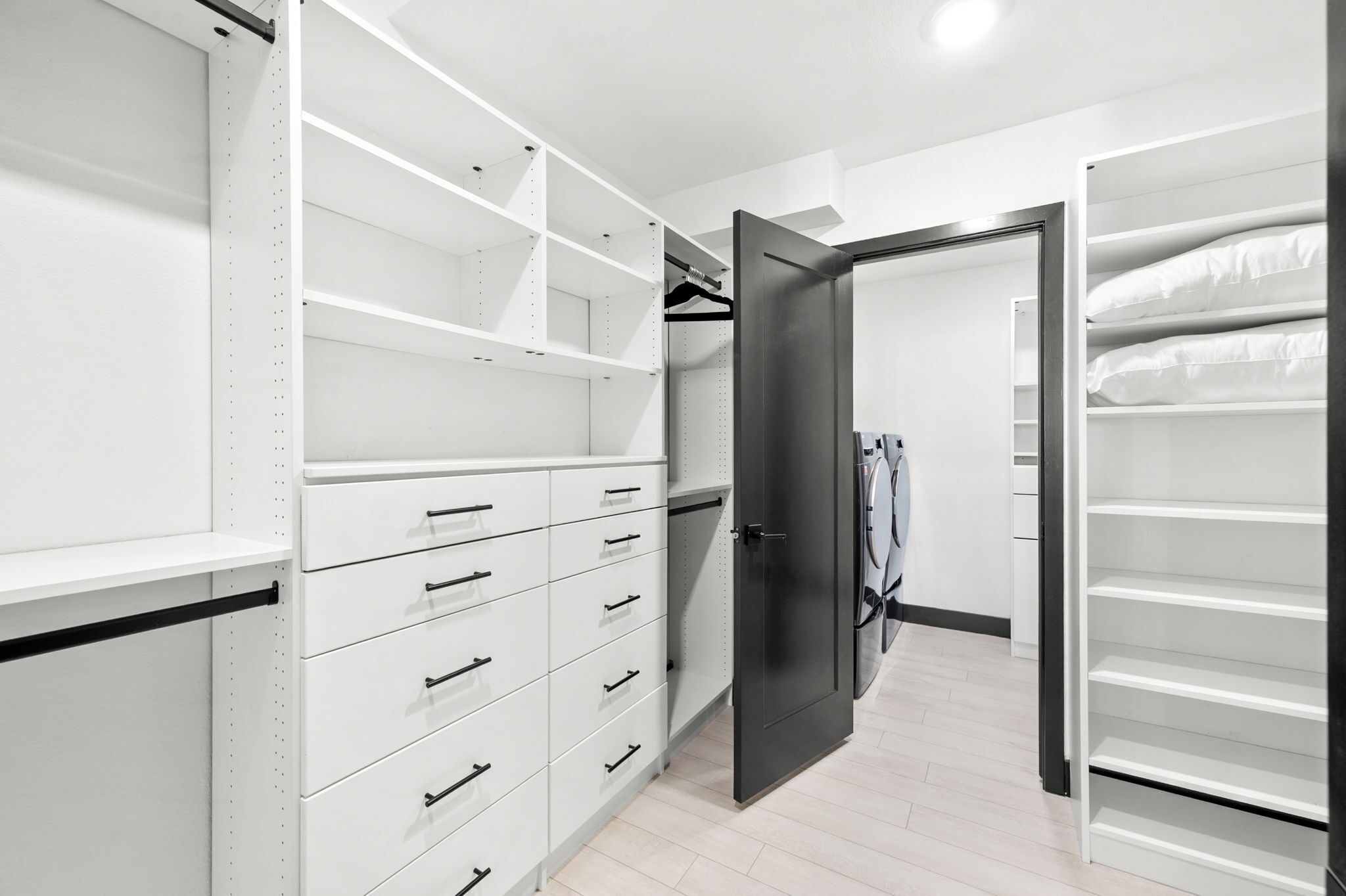 A walk-in closet with open doors, shelves, and drawers.