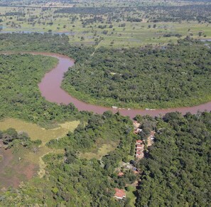 An aerial view of a river winding through a densely forested area with scattered buildings.