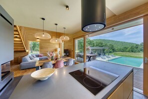 Een moderne keuken met een groot eiland, een eetgedeelte en uitzicht op een zwembad.