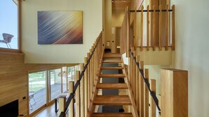 A wooden staircase with a handrail, a painting on the wall, and a view of the outdoors. - Villa Lovelos with Infinity Pool in Nature (Lovinac)