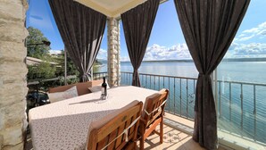 A balcony with a table and chairs, a bottle, and a view of the sea. - Apartment Laura 1 by the Sea (Maslenica)