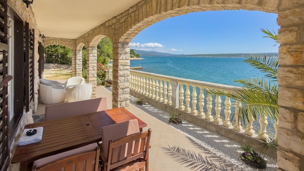 Un'area salotto all'aperto ad arco in pietra con vista sul mare.