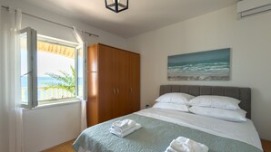 Una camera da letto con un letto, una finestra con tende, un armadio e un quadro appeso al muro.