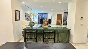 A dining area with a green table and chairs, a decorative centerpiece, and a view into the living room. - Luxurious 7-bedroom Villa in La Marsa, Tunisia - Modern Comfort & Elegance (La Marsa)