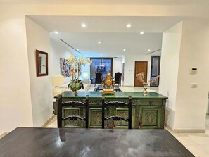 A dining area with a green table and chairs, a decorative centerpiece, and a view into the living room. - Luxurious 7-bedroom Villa in La Marsa, Tunisia - Modern Comfort & Elegance (La Marsa)