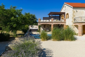 A stone house with a pool, surrounded by greenery and a clear sky. - Villa Gland with Pool and Whirlpool (Nin)