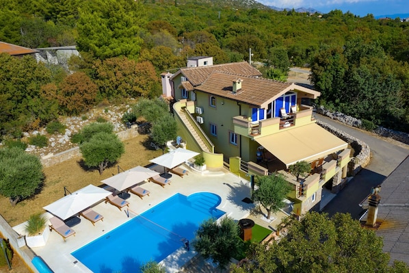 A two-story building with a swimming pool, outdoor seating, and a view of the surrounding greenery. - Villa Paulina with Heated Pool (Starigrad)