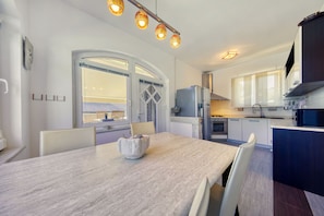 A modern kitchen with a dining area, featuring a large table, chairs, and a view through a window. - Villa Paulina with Heated Pool (Starigrad)