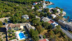 Ett flygbildsbild av ett bostadsområde vid kusten med hus, en swimmingpool och en småbåtshamn.