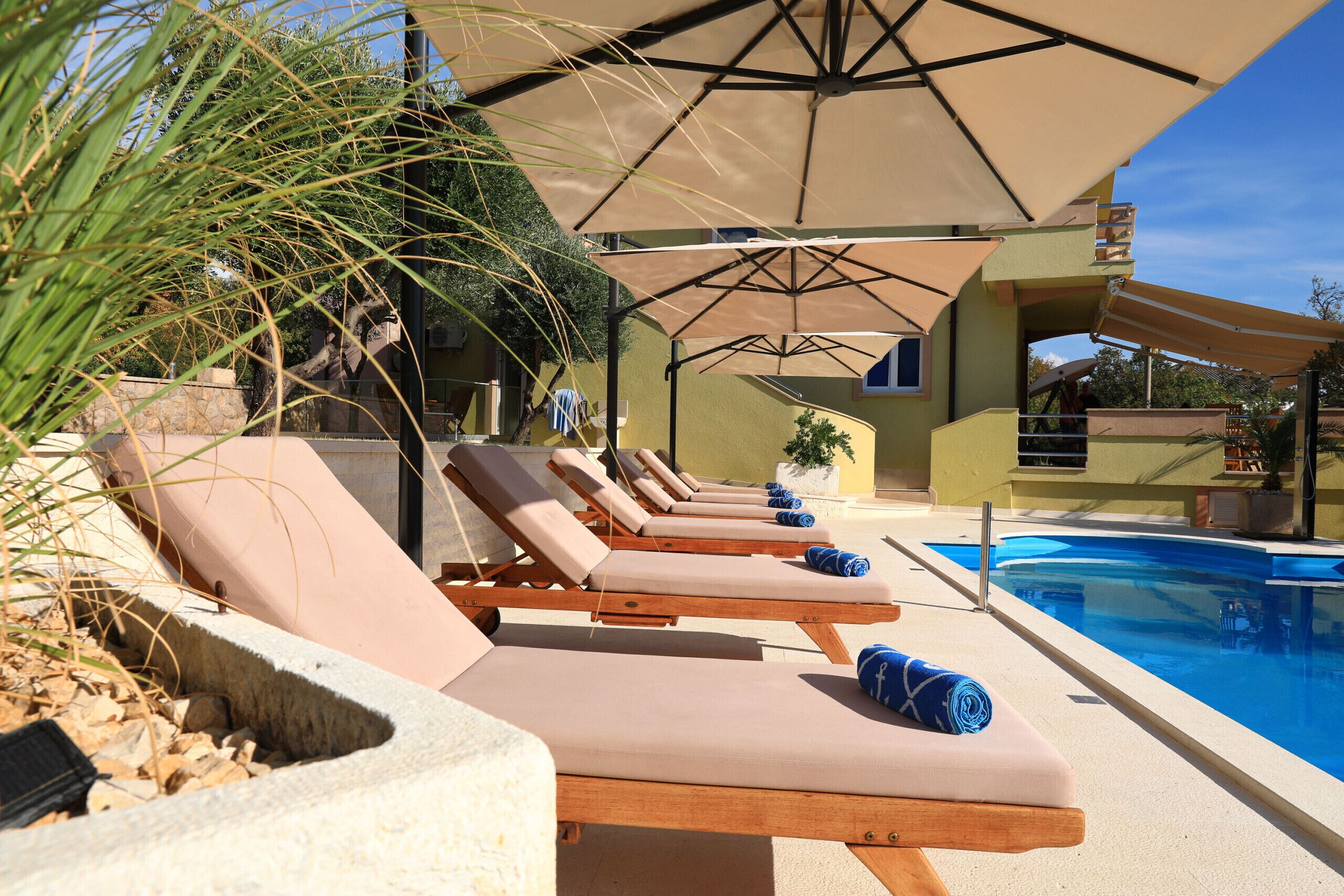 A poolside area with lounge chairs, umbrellas, and a swimming pool.