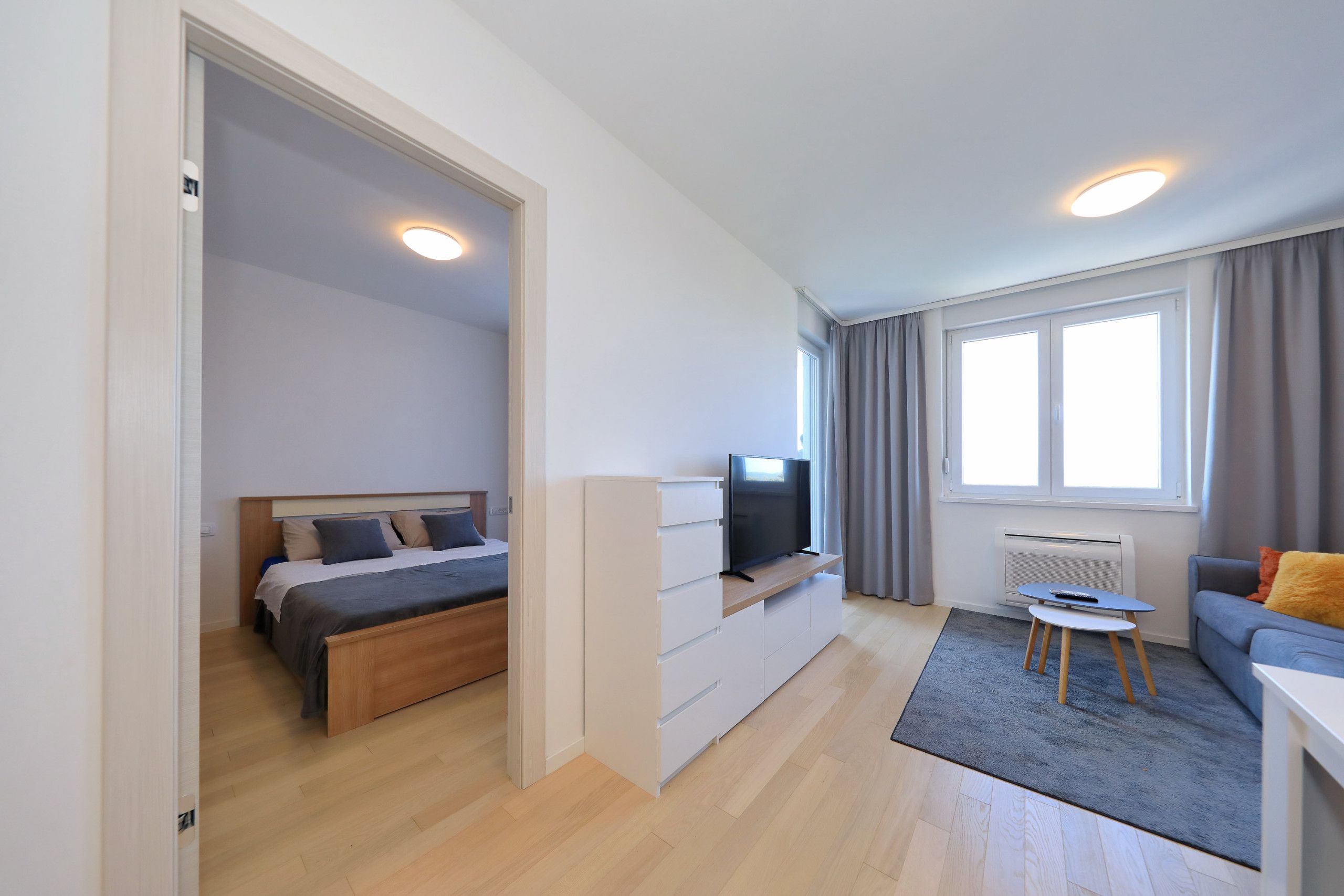 Ein modernes Hotelzimmer mit Bett, Fernseher, Sofa und einem kleinen Tisch.