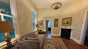 Uma sala de estar com um sofá, um tapete estampado, uma lareira e um candelabro.