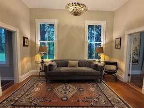 Una habitación con sofá, dos lámparas, alfombra y candelabro.
