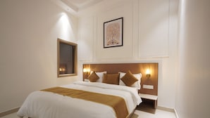 Un dormitorio con una cama grande, una mesita de noche, una lámpara de pared e imagen enmarcada sobre la cama.