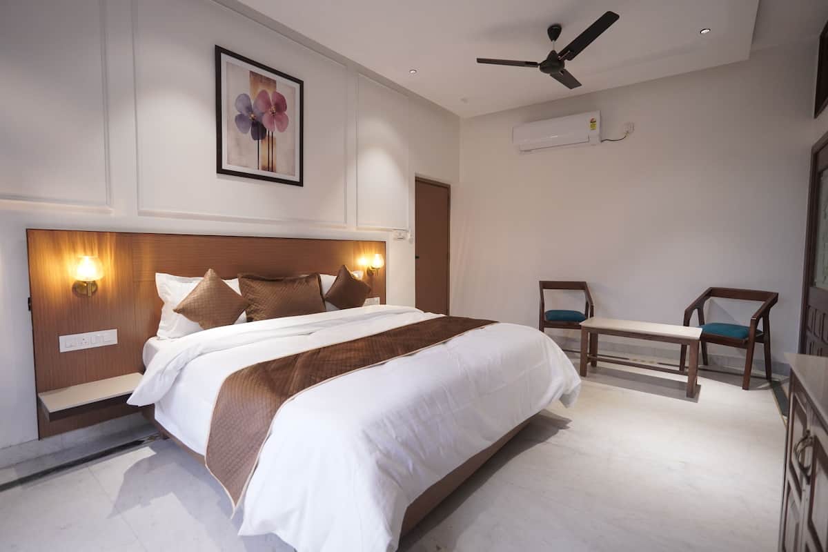 Un dormitorio moderno con una cama grande, lámparas de noche, un ventilador de techo y un banco.