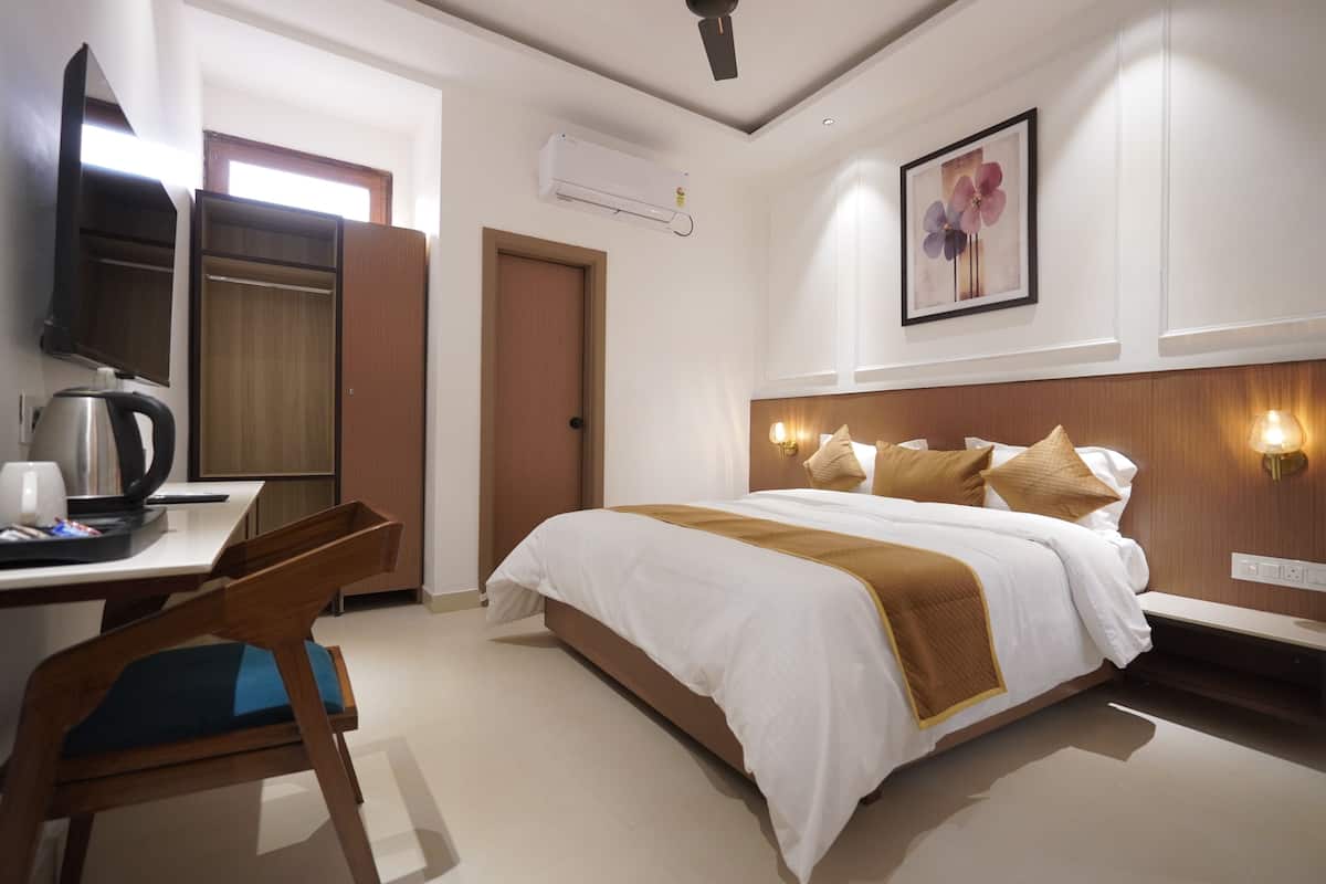 Habitación de hotel con cama, escritorio, silla, televisor y aire acondicionado instalado en la pared.