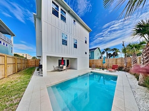 A two-story house with a swimming pool, a patio with outdoor furniture, and a wooden fence. - Ocean Retreat | Two Luxury Homes w/Private Pools (St. Augustine)