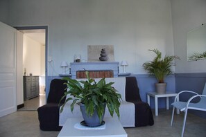 Ein Wohnzimmer mit einer Couch, einem Couchtisch mit Pflanze, einem Kamin und einem Spiegel an der Wand.