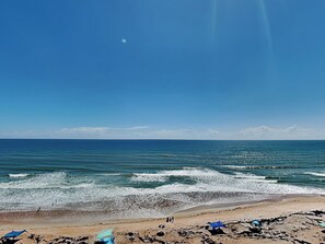 Ein Strand mit Wellen, einem klaren Himmel und einem sichtbaren Mond.
