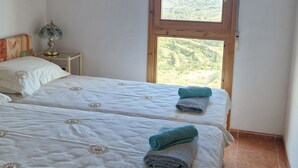 A bedroom with two beds, a nightstand, a lamp, a framed picture, and a window with a view. - Serenity - pool, mountains and incredible views, near the Relleu footbridge. (Relleu)