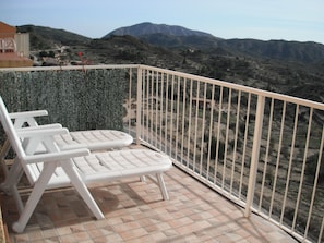 A balcony with two white lounge chairs, a tiled floor, and a view of a hilly landscape. - Serenity - pool, mountains and incredible views, near the Relleu footbridge. (Relleu)