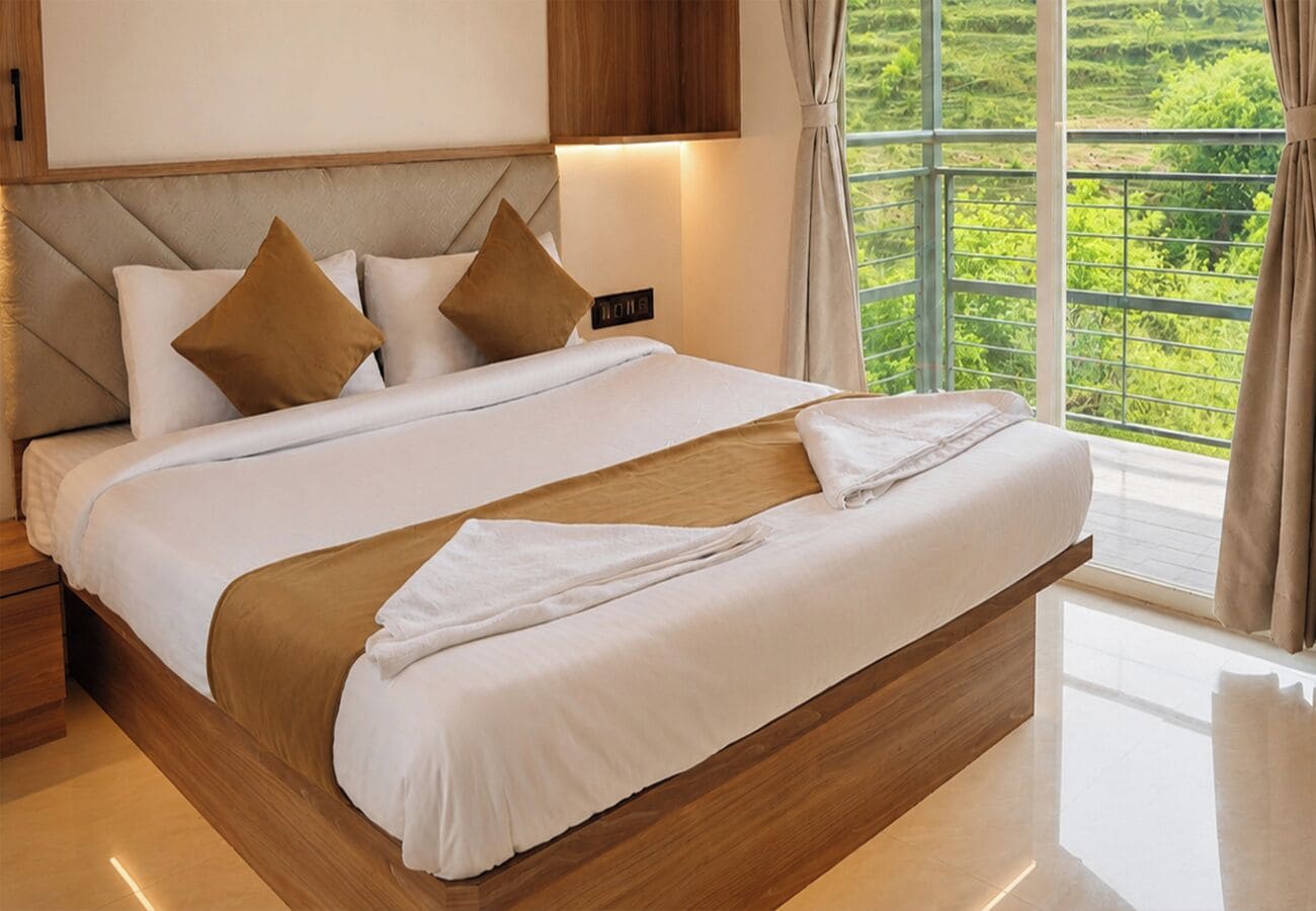 A large bed with a wooden headboard, white bedding, and two brown pillows.